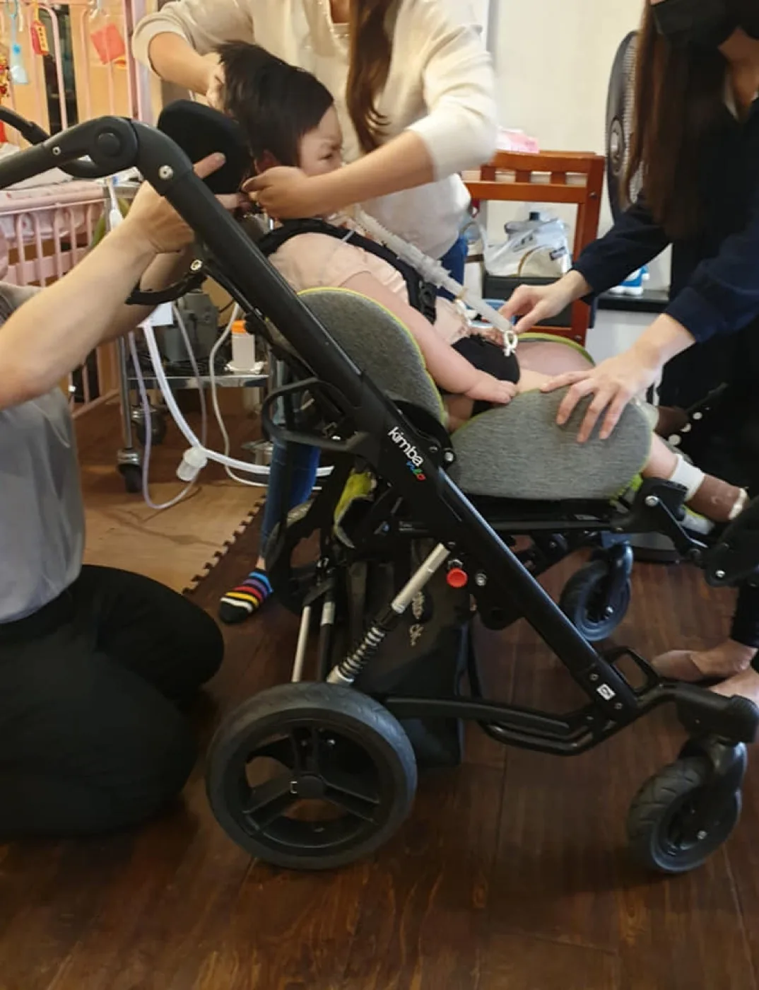 孩子坐在特製擺位推車上,展現居家輔具協助氣切兒童外出的樣子。