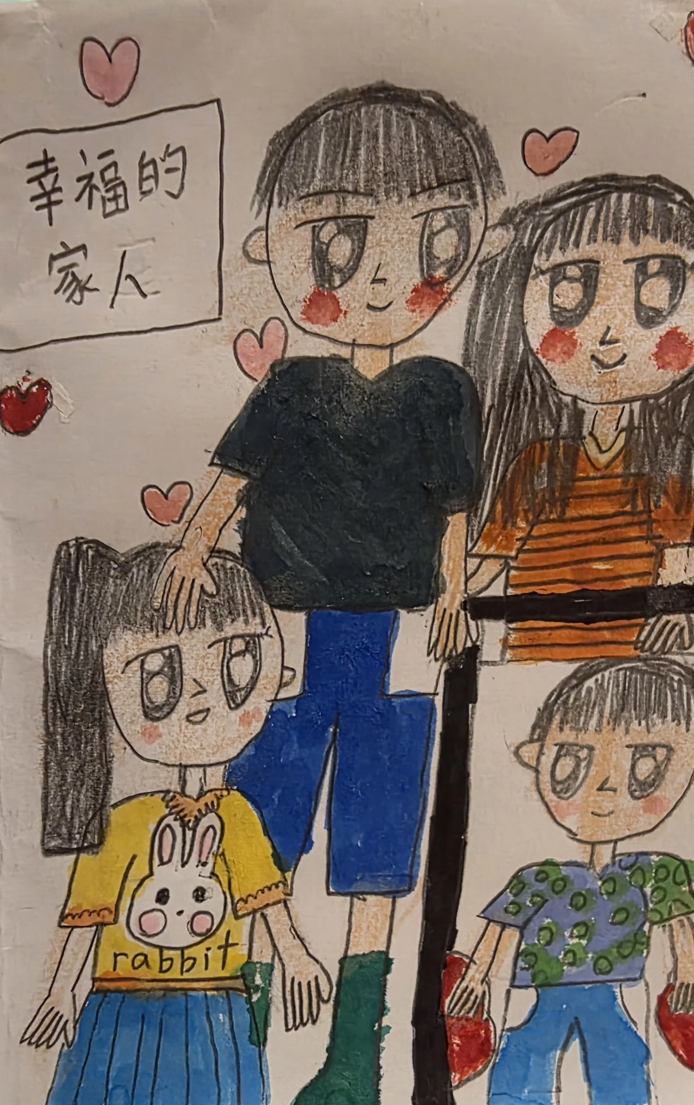 一張手繪的全家福，畫面左上角框著「幸福的家人」四個字，四周散布著粉紅與紅色的愛心。畫中共四個人：後排是一位穿深色上衣、藍色長褲的大人，以及一位長髮、穿橘色條紋上衣的人；前排左邊是一個綁著長髮、穿黃色兔子圖案上衣的女孩，右邊是一個穿綠色點點上衣的孩子，身旁有一根黑色直桿。
